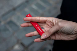 A woman holds a Puff Bar flavored disposable vape device.