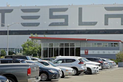 In this Monday, May 11, 2020 file photo, a man wearing a mask walks through the Tesla plant parking lot in Fremont, Calif. On Wednesday, July 22, 2020, the electric car maker announced it has picked the Austin, Texas, area as the site for its largest auto assembly plant employing at least 5,000 workers.