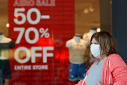 In this June 10, 2020 file photo, a woman walks past a store with sale signs displayed at Great Lakes Mall, in Mentor, Ohio. The Federal Reserve says economic activity has picked up in most regions of the country but still remains well below pre-pandemic levels with the country facing high levels of uncertainty. The Fed reported Wednesday, July 15 that its latest survey of economic conditions around the country found improvements in consumer spending and other areas but said the gains were from very low levels seen when widespread lockdowns push the country into a deep recession.