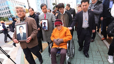 Kim Sung-joo, bottom center, a victim of Japan's forced labor, arrives at the Supreme Court's in Seoul, South Korea.