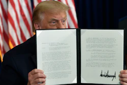 President Donald Trump signs an executive order during a news conference at the Trump National Golf Club.