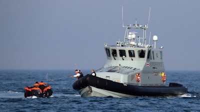 A Border Force vessel assist a group of people thought to be migrants on board from their inflatable dinghy in the Channel.