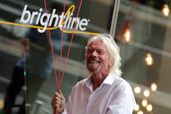 Richard Branson, of Virgin Group, prepares to unfurl a banner during a naming ceremony for the Brightline train station.