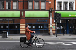 A woman rides a bicycle past a job center in Shepherd's Bush, London, April 30, 2020.