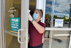 Kendall Ballew, an employee of the Anderson Mall, cleans the doors before the mall opened to limited business in Anderson, S.C.