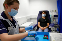 Clinical Research Nurse Aneta Gupta labels blood samples from volunteer Yash during the Imperial College vaccine trial, at a clinic in London, Wednesday, Aug. 5, 2020. Scientists at Imperial College London are immunizing hundreds of people with an experimental coronavirus vaccine in an early trial after seeing no worrying safety problems in a small number vaccinated so far.