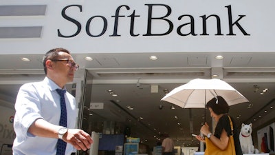 In this Aug. 7, 2019, file photo, people walk by a SoftBank shop in Tokyo. Japanese technology conglomerate SoftBank Group Corp. saw its April-June profit rise 12% as its investments added to its coffers, including sales of U.S. carrier T-Mobile shares.