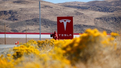 In this Oct. 13, 2018 file photo, a sign marks the entrance to the Tesla Gigafactory in Sparks, Nev. Tesla CEO Elon Musk solved a mystery involving a 27-year-old Russian who prosecutors say flew to the United States to offer a major-company insider $1 million to assist in a ransomware extortion attack on the firm. According to the billionaire, the scheme took aim at the electric car company’s 1.9 million-square-foot factory in Sparks, Nevada, which makes batteries for Tesla vehicles and energy storage units.