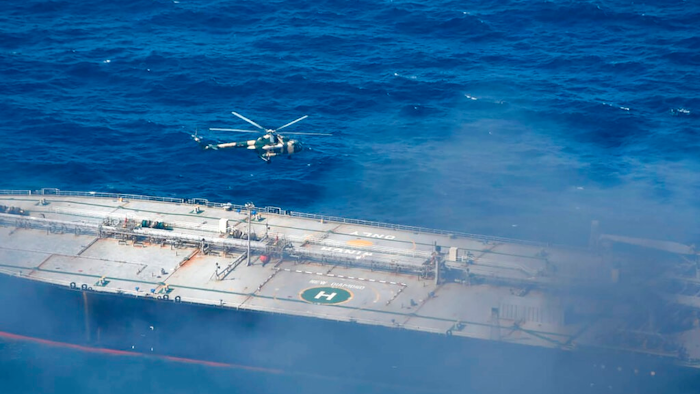 In this photo provided by Sri Lanka Air Force, a chopper flies through smoke rising from the MT New Diamond, off the eastern coast of Sri Lanka in the Indian Ocean,, Saturday, Sept. 5, 2020. The fire on the large oil tanker off Sri Lanka's coast has been brought under control but is still not extinguished, the navy said Saturday. The tanker, carrying nearly 2 million barrels of crude oil, was drifting about 20 nautical miles (37 kilometers) from Sri Lanka's eastern coast and on Friday evening a tug boat towed it to the deep sea away from land, said navy spokesman Capt. Indika de Silva.