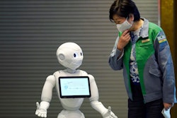 Humanoid robot Pepper, wearing a face mask, greets Tokyo Gov. Yuriko Koike in the lobby of a hotel for COVID-19 patients with mild symptoms, May 1, 2020, in Tokyo.