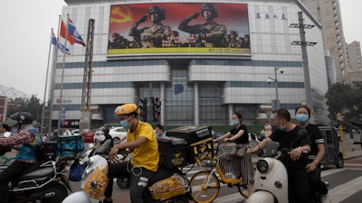 Residents wearing mask to protect themselves from contracting the coronavirus pass by a Chinese military propaganda display in Beijing.