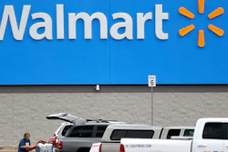 A woman pulls groceries from a cart to her vehicle outside of a Walmart store.
