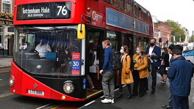 People board a bus outside Waterloo station in London.