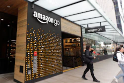 In this March 4, 2020 file photo, people walk out of an Amazon Go store, in Seattle. Amazon is rolling out a new device for contactless transactions that will scan an individual’s palm. The Amazon One, which will initially launch in two Amazon Go stores in Seattle, is being viewed as a way for people to use their palm to make everyday activities like paying at a store easier.