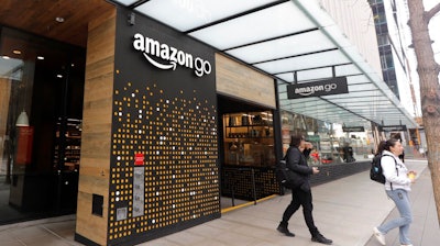 In this March 4, 2020 file photo, people walk out of an Amazon Go store, in Seattle. Amazon is rolling out a new device for contactless transactions that will scan an individual’s palm. The Amazon One, which will initially launch in two Amazon Go stores in Seattle, is being viewed as a way for people to use their palm to make everyday activities like paying at a store easier.