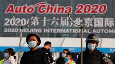 Security guards wearing masks and armed with restrainers stand guard at the entrance to the Auto China 2020 show in Beijing, China on Saturday, Sept. 26, 2020. The auto show, the first major in-person sales event for any industry since the coronavirus pandemic began, opens Saturday in a sign the ruling Communist Party is confident China has contained the disease. Still, automakers face intensive anti-virus controls including quarantines for visitors from abroad and curbs on crowd sizes at an event that usually is packed shoulder-to-shoulder with spectators.