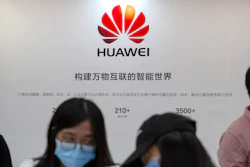 Visitors wearing face masks to protect against the coronavirus stand at a booth for Chinese technology firm Huawei at the China International Fair for Trade in Services (CIFTIS) in Beijing.
