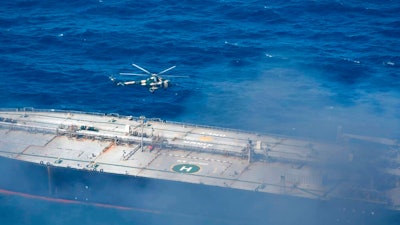 In this photo provided by Sri Lanka Air Force, a chopper flies through smoke rising from the MT New Diamond, off the eastern coast of Sri Lanka in the Indian Ocean,, Saturday, Sept. 5, 2020. The fire on the large oil tanker off Sri Lanka's coast has been brought under control but is still not extinguished, the navy said Saturday. The tanker, carrying nearly 2 million barrels of crude oil, was drifting about 20 nautical miles (37 kilometers) from Sri Lanka's eastern coast and on Friday evening a tug boat towed it to the deep sea away from land, said navy spokesman Capt. Indika de Silva.