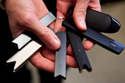 In this April 16, 2019 file photo, a researcher holds vape pens in a laboratory in Portland, Ore. According to a Centers for Disease Control and Prevention report released on Wednesday, Sept. 9, 2020, vaping rates among U.S. teenagers fell dramatically in 2020. The drop comes in the wake of 2019’s outbreak of vaping-related illnesses and deaths.