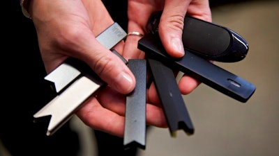 In this April 16, 2019 file photo, a researcher holds vape pens in a laboratory in Portland, Ore. According to a Centers for Disease Control and Prevention report released on Wednesday, Sept. 9, 2020, vaping rates among U.S. teenagers fell dramatically in 2020. The drop comes in the wake of 2019’s outbreak of vaping-related illnesses and deaths.