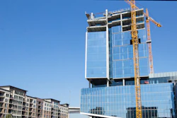 Construction workers place a tarp over an opening on the first level of the Marathon Oil building.