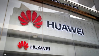 Logos of Huawei are displayed at its retail shop window with the reflection of the Ministry of Foreign Affairs office in Beijing.