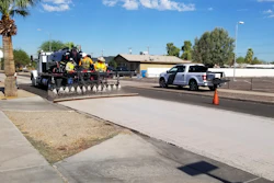 A City of Phoenix Street Transportation Department crew sprays light-colored pavement over blacktop on a street in the Garfield District of Phoenix, Aug. 11, 2020.