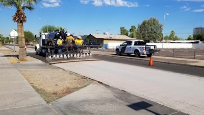 A City of Phoenix Street Transportation Department crew sprays light-colored pavement over blacktop on a street in the Garfield District of Phoenix, Aug. 11, 2020.