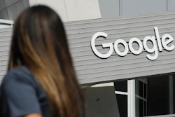 A woman walks below a Google sign on the campus in Mountain View, Calif.