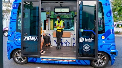 Deployment Manager Jason Peres, center, explains how Relay, an electric autonomous vehicle, works to new riders in Fairfax, Va.