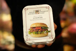 A store clerk shows a plant-based burger at a supermarket chain in Brussels on Friday, Oct. 23.