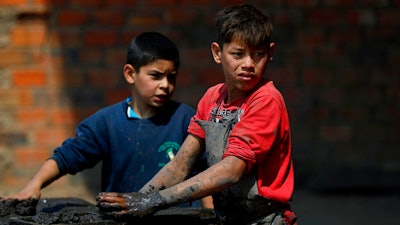 Mauri, 11, left, and Cesar, 13, work at a clay brick factory in Tobati, Paraguay, Friday, Sept. 4, 2020. The boys have been working at the factory, run by Mauri's family, since before schools stopped operating in March amid the COVID-19 pandemic.