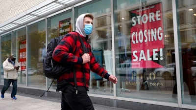 A passer-by walks past a store closing sign, right, in the window of a department store, Tuesday, Oct. 27, 2020, in Boston. Americans may feel whiplashed by a report Thursday, Oct. 29, on the economy's growth this summer, when an explosive rebound followed an epic collapse. The government will likely estimate that the economy grew faster on an annualized basis last quarter than in any such period since record-keeping began in 1947.