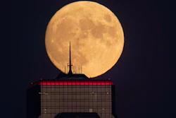 A nearly full moon rises behind an office building in Kansas City, Mo., Sept. 30, 2020.