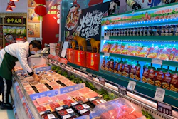 A worker wearing a mask handles meat products including beef from New Zealand packaged with a QR-code linked to its COVID test results at a supermarket in Beijing, Tuesday, Nov. 24, 2020.
