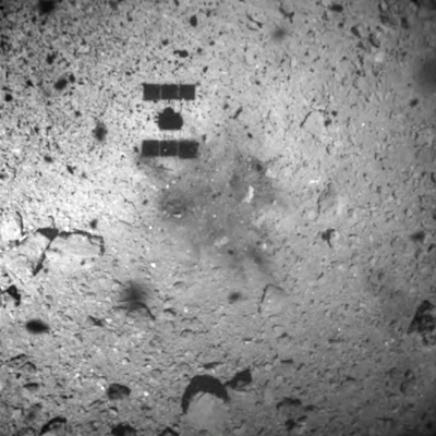 This Feb. 22, 2019, file image released by the Japan Aerospace Exploration Agency (JAXA) shows the shadow, center above, of the Hayabusa2 spacecraft after its successful touchdown on the asteroid Ryugu. The Japanese spacecraft is nearing Earth after a yearlong journey home from a distant asteroid carrying soil samples and data that could provide clues to the origins of the solar system, a space agency official said Friday, Nov. 27, 2020.