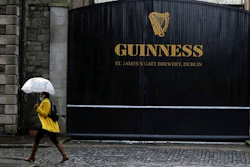 A woman passes the Guinness brewery in Dublin's city centre Wednesday Nov. 11, 2020. Irish brewer Guinness announced Wednesday it is recalling cans of its recently launched non-alcoholic stout in Britain, as a precautionary measure over contamination concerns.