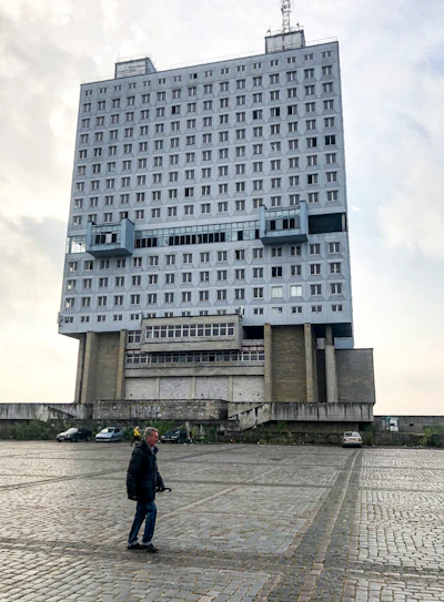 A man walks past the never-occupied building in Kaliningrad, Russia, Thursday, Oct. 29, 2020. The hulking never-occupied building sardonically likened to a robot's head that has loomed over the city of Kaliningrad for decades is to be demolished next year, the region's governor says. The 21-story House of Soviets was left unfinished when funding ran out in 1985 amid the Soviet Union's economic struggles and later was assessed to be structurally unsound.