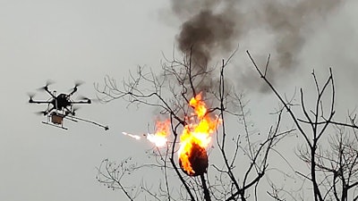 In this Dec. 10, 2020, photo released by Blue Sky Rescue of Zhong County, a drone equipped with a flamethrower burns a wasp nest at a village in Zhong county near Chongqing municipality in southwestern China. A drone has been converted into the flying flamethrower in central China in a fiery campaign to eradicate more than 100 wasp nests.