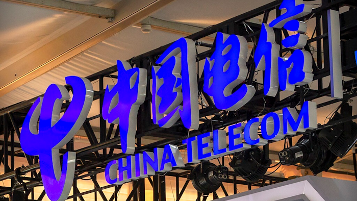 In this Sept. 5, 2020, file photo, the logo for Chinese telecommunications firm China Telecom is seen on a booth at the China International Fair for Trade in Services (CIFTIS) in Beijing. The New York Stock Exchange says it no longer plans to remove shares of three Chinese state-owned phone carriers under an order by President Donald Trump.