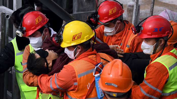 In this photo released by Xinhua News Agency, rescuers carry a miner who was trapped in a mine to an ambulance in Qixia City in east China's Shandong Province.
