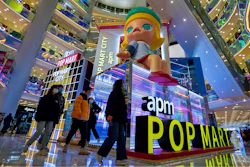 Shoppers wearing face masks to help curb the spread of the coronavirus wall by the Chinese toy maker POP Mart display booth at a shopping mall in Beijing on Dec. 9, 2020.