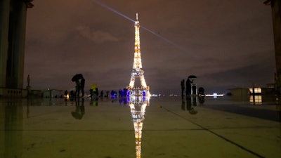 People stroll on the Trocadero square to watch the Eiffel Tower lightings, Friday, Dec. 11, 2020 in Paris.