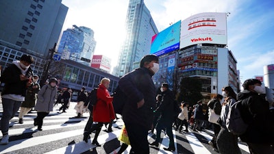 People wearing protective masks to help curb the spread of the coronavirus walk along pedestrian crossings Monday, Jan. 25, 2021 in Tokyo. The Japanese capital confirmed more than 600 new coronavirus cases on Monday.