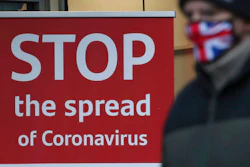 A man wearing a British union flag face mask walks past a coronavirus advice sign outside a bank in Glasgow the morning after stricter lockdown measures came into force for Scotland, Tuesday Jan. 5, 2021. Further measures were put in place Tuesday as part of lockdown restrictions in a bid to halt the spread of the coronavirus.