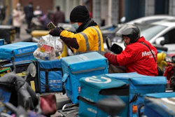 A food delivery worker wearing a face mask to help curb the spread of the coronavirus prepares to deliver foods for his customers outside a restaurant in Beijing on Thursday, Jan. 14, 2021. The e-commerce workers and delivery people who kept China fed during the pandemic, making their billionaire bosses even richer, are so unhappy with their pay and treatment that one just set himself on fire in protest.
