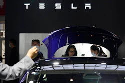 In this Sunday, Sept. 27, 2020, file photo, attendees wearing masks to protect from the coronavirus look at cars at the Tesla booth during the Auto China 2020 show in Beijing. Tesla Inc. is balking at recalling about 159,000 vehicles with potentially defective touch screens, so U.S. safety regulators are moving to force the company to take action, in news announced Wednesday, Jan. 13, 2021.
