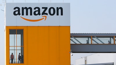 In this April 9, 2020 photo, employees observe social distancing due to coronavirus, at the entrance of Amazon, in Douai, northern France.