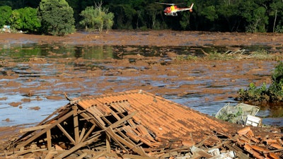 Rescue workers in a helicopter search a flooded area after a dam collapsed in Brumadinho, Brazil, Jan. 27, 2019.