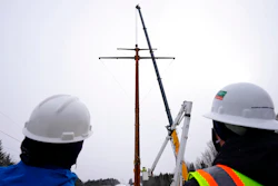 Workers watch the installation of the first pole of Central Maine Power's controversial hydropower transmission corridor near The Forks, Maine, Feb. 9, 2021.